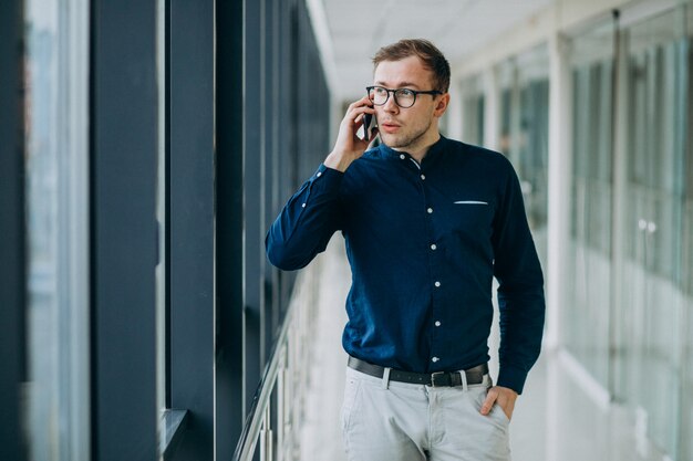 Giovane uomo bello parlare al telefono in ufficio