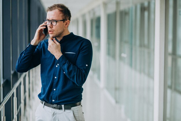 Giovane uomo bello parlare al telefono in ufficio