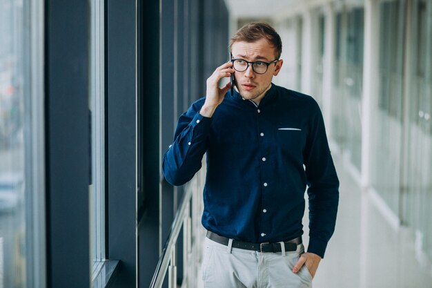 Giovane uomo bello parlare al telefono in ufficio