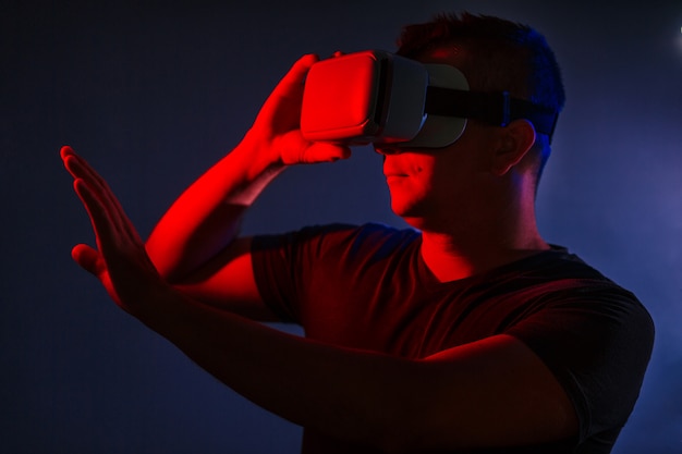 Giovane uomo casual astuto che indossa la cuffia avricolare vr di realtà virtuale che gesturing le mani