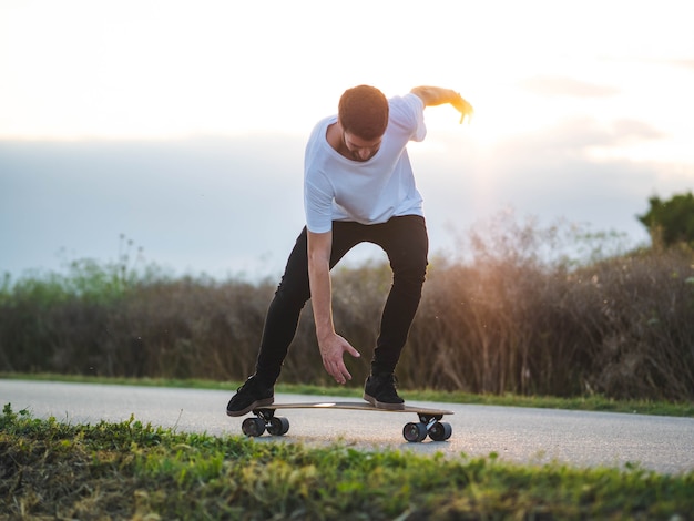 Giovane uomo caucasico che fa acrobazie con uno skateboard per strada