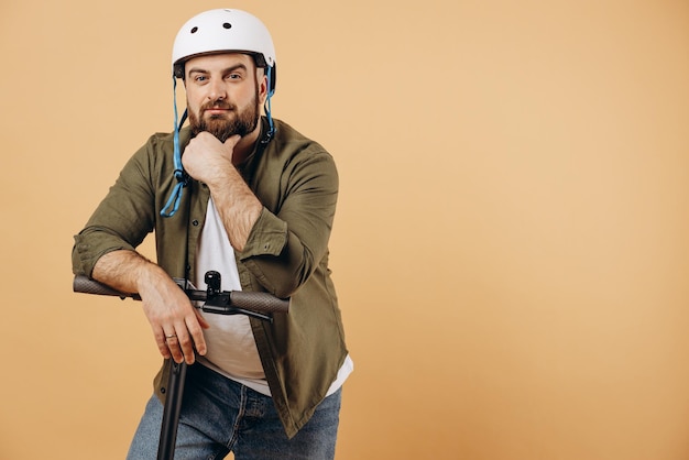 Giovane uomo che indossa il casco di sicurezza e guida uno scooter elettrico