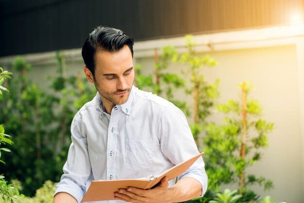 Giovane uomo che legge un libro nel parco in un giorno d&#39;estate.