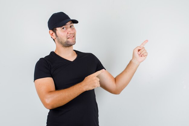 Giovane uomo che punta le dita a lato in maglietta nera