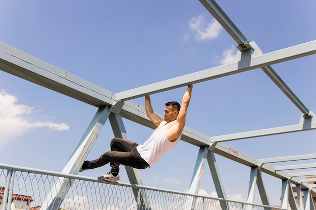 Giovane uomo che si arrampica sul soffitto di un ponte