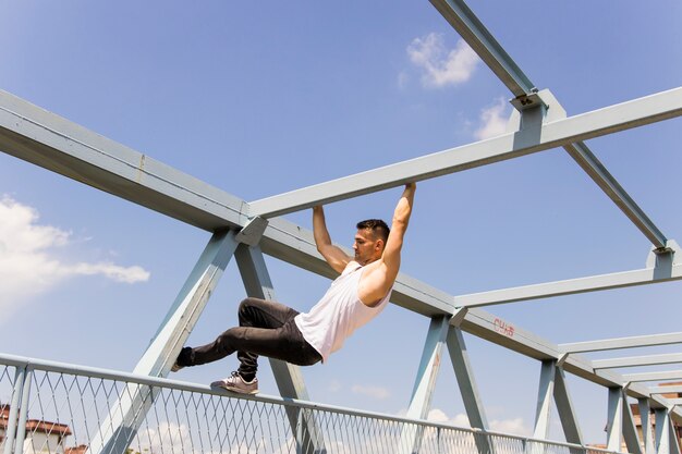 Giovane uomo che si arrampica sul soffitto di un ponte