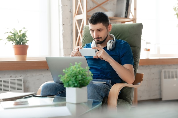 Giovane uomo concentrato che studia a casa durante i corsi online o informazioni gratuite da solo