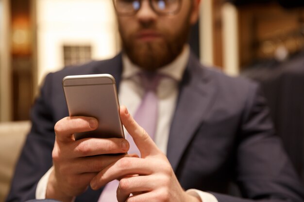 Giovane uomo d'affari barbuto concentrato che chiacchiera dal telefono