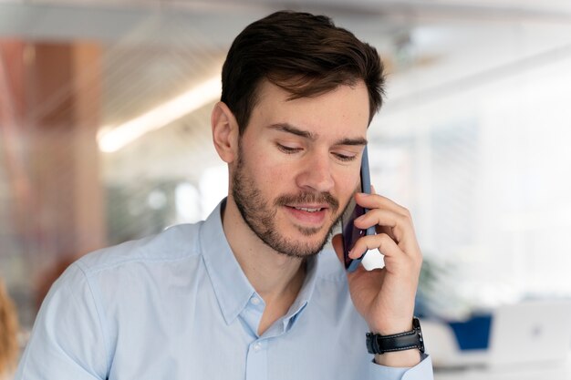 Giovane uomo d'affari che lavora alla sua scrivania con lo smartphone