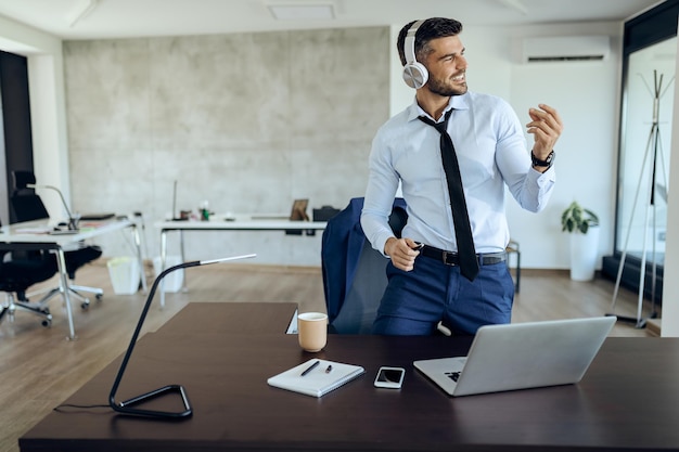 Giovane uomo d'affari che si diverte ascoltando musica in cuffia in ufficio