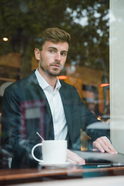 Giovane uomo d&#39;affari che si siede nel caffè con il computer portatile