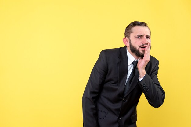 Giovane uomo d'affari che soffre di mal di denti su giallo