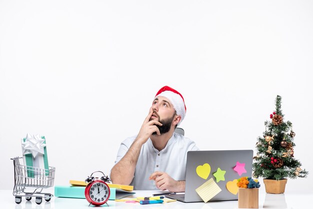 Giovane uomo d'affari confuso in ufficio che celebra il nuovo anno o il natale lavorando da solo