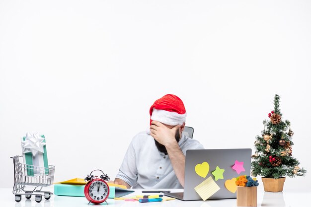 Giovane uomo d'affari esausto e occupato con il cappello di babbo natale che lavora da solo