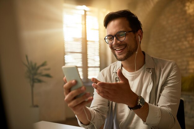 Giovane uomo d'affari felice utilizzando il telefono cellulare mentre si lavora in ufficio