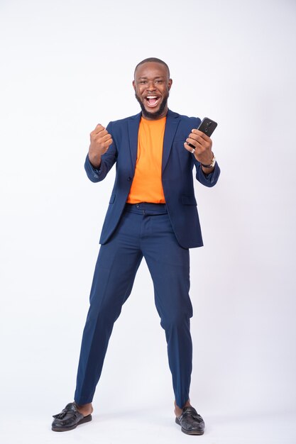 Giovane uomo d'affari nigeriano sorpreso che celebra mentre guarda il suo telefono