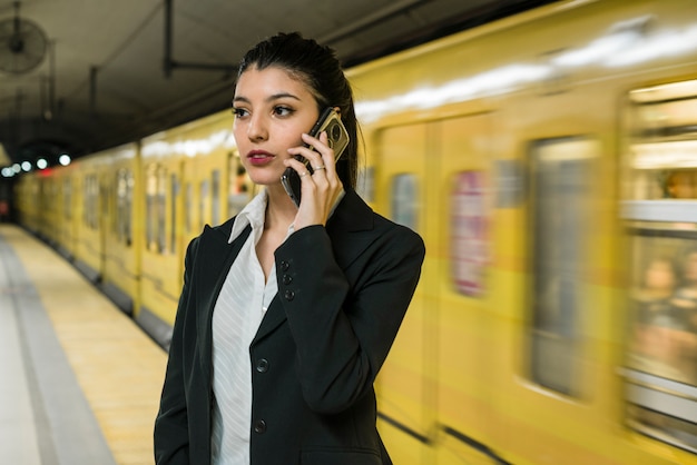 Giovane uomo d&#39;affari sicuro che parla sul telefono cellulare che sta vicino al treno giallo commovente
