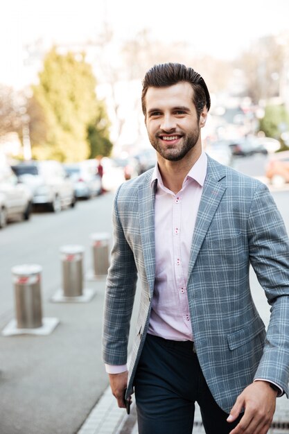 Giovane uomo d'affari sorridente che cammina all'aperto.