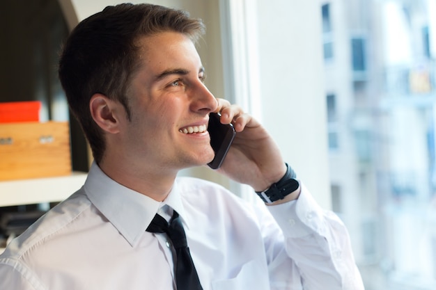 Giovane uomo d&#39;affari utilizzando il suo telefono cellulare in carica.