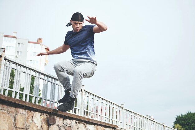 Giovane uomo di sport che fa parkour in città.