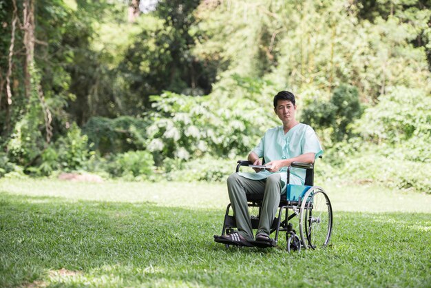 Giovane uomo disabile da solo in sedia a rotelle al giardino