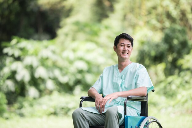 Giovane uomo disabile da solo in sedia a rotelle al giardino