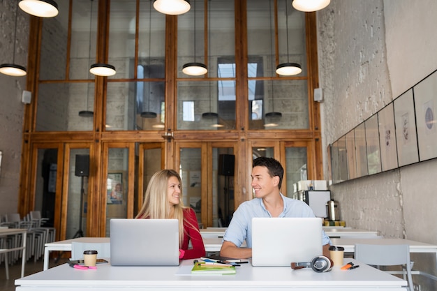 Giovane uomo e donna che lavorano su laptop in open space co-working office room,