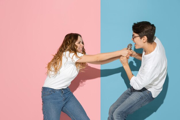 Giovane uomo e donna emotivi sul muro rosa e blu