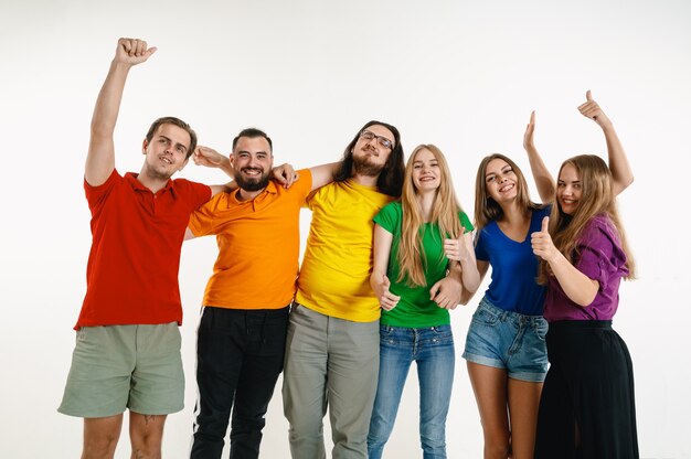 Giovane uomo e donna indossati nei colori della bandiera Lgbt sul muro bianco