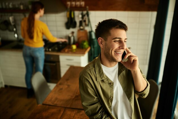 Giovane uomo felice che parla al cellulare a casa