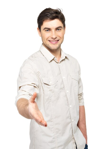Giovane uomo felice con il gesto della stretta di mano in casuals isolato sul muro bianco.