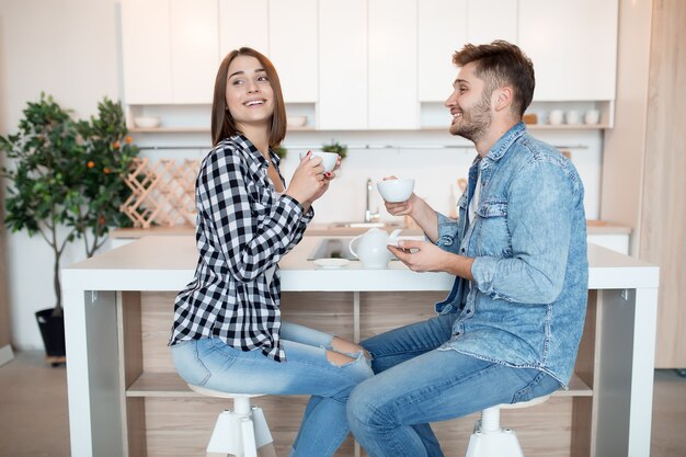 Giovane uomo felice e donna in cucina, colazione, coppia insieme al mattino, sorridente, tè