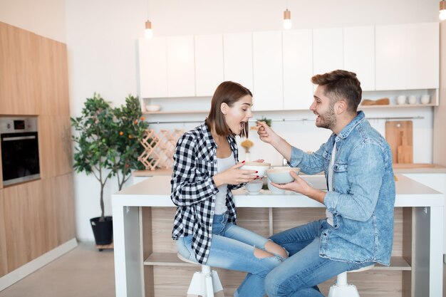 Giovane uomo felice e donna in cucina, fare colazione, coppia insieme al mattino, sorridendo