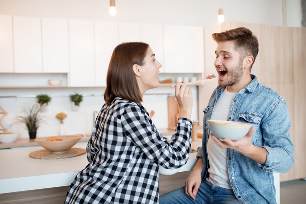 Giovane uomo felice e donna in cucina, fare colazione, coppia insieme al mattino, sorridendo