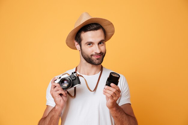 Giovane uomo fiducioso tenendo la fotocamera e l'obiettivo in mano