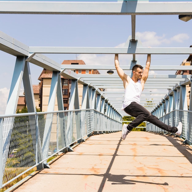 Giovane uomo in buona salute che appende sul ponte