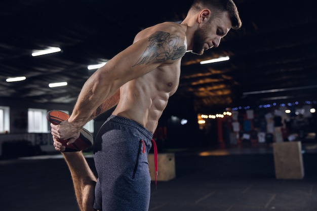 Giovane uomo in buona salute facendo esercizi, stretching in palestra