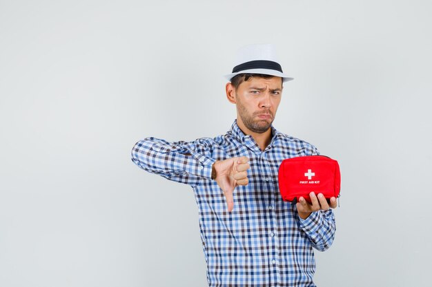 Giovane uomo in camicia a quadri, cappello tenendo il kit di pronto soccorso