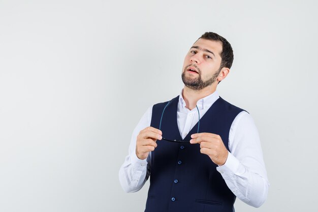 Giovane uomo in camicia, gilet con gli occhiali e guardando fiducioso