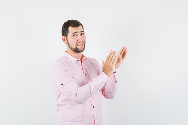 Giovane uomo in camicia rosa che applaude dopo la presentazione in conferenza e sembra soddisfatto