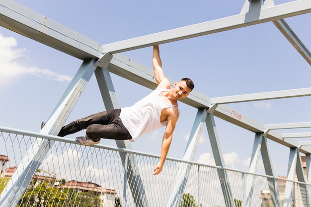 Giovane uomo in equilibrio sulla ringhiera di un ponte