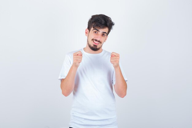 Giovane uomo in maglietta che mostra il segno del fico e sembra divertente
