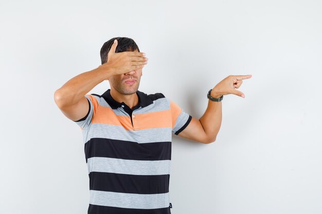 Giovane uomo in maglietta che mostra un segno di piccole dimensioni, che copre gli occhi