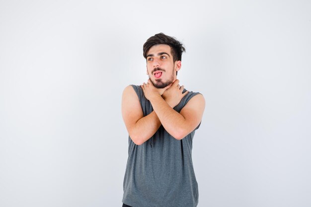 Giovane uomo in maglietta grigia che tiene le braccia incrociate, distoglie lo sguardo e sembra serio