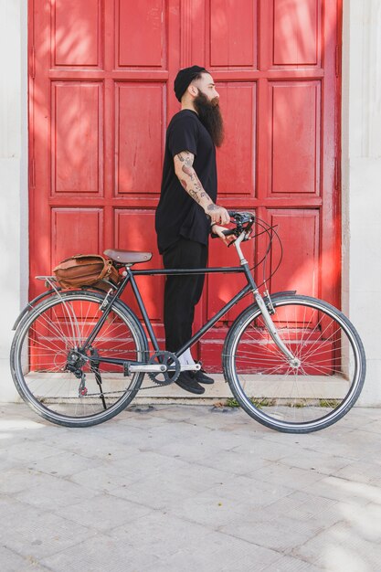Giovane uomo in piedi con la sua bicicletta in cerca di qualcuno
