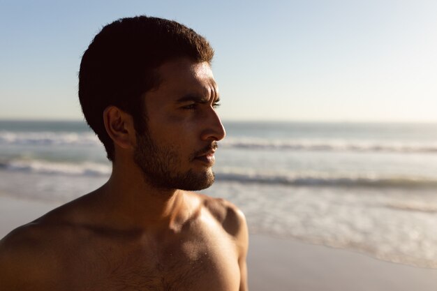 Giovane uomo in piedi sulla spiaggia