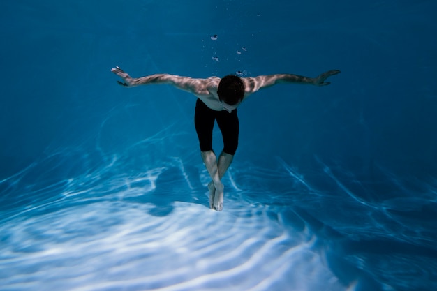 Giovane uomo in posa sommerso sott'acqua