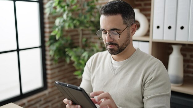 Giovane uomo ispanico lavoratore d'affari che usa il touchpad che lavora in ufficio