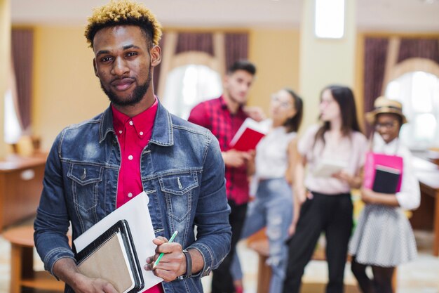 Giovane uomo nero che propone con i libri