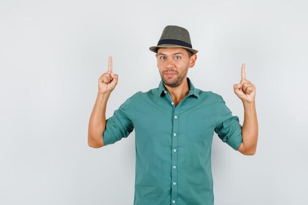 Giovane uomo rivolto verso l'alto le dita in camicia, cappello e guardando fiducioso